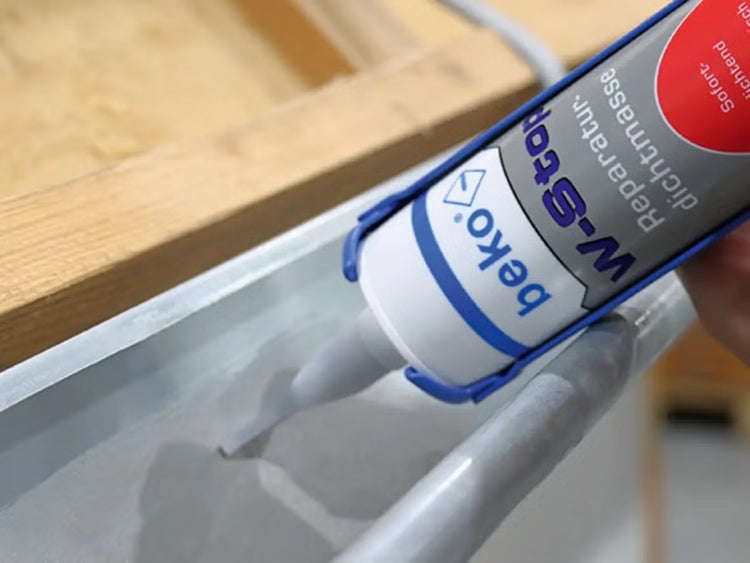 Eine Kartusche beko W-Stop Reparatur-Dichtmasse wird auf eine Dachrinne aus Metall aufgetragen.