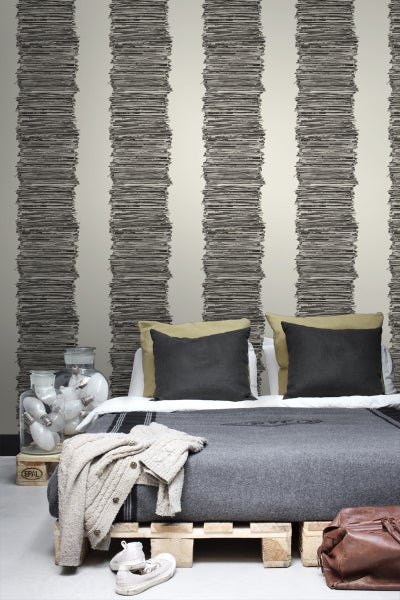 Ein Schlafzimmer mit einer gestreiften Tapete, die aus übereinander gestapelten Dokumenten besteht