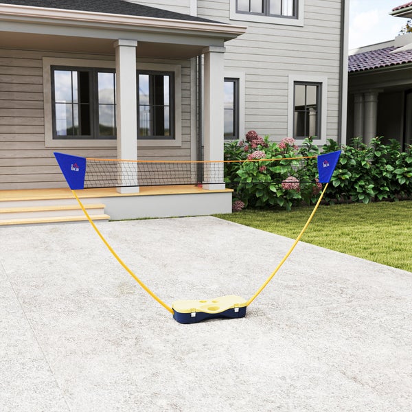 Mobiles Badminton- und Tennisnetz-Set mit gelber Basis und flexiblen Stangen auf einer hellen Terrasse vor einem Wohnhaus im Garten.