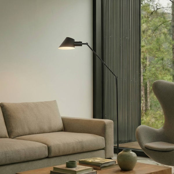 Stehlampe neben Sofa und Sessel in einem Wohnzimmer.