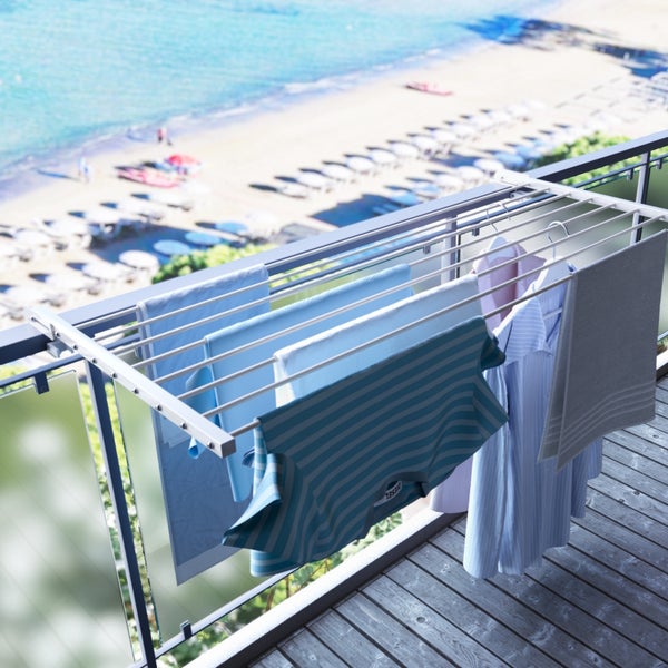 Wäscheständer mit daran hängender Kleidung auf einem Balkon mit Meerblick
