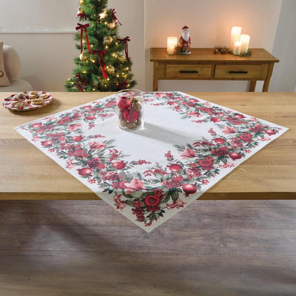 Quadratische Tischdecke mit weihnachtlichem Blumen und Beeren Motiv auf einem Holztisch in festlichem Wohnambiente.