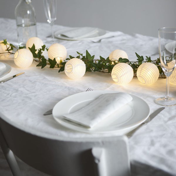 Festlich gedeckter Tisch mit Lichterkette und Dekoration