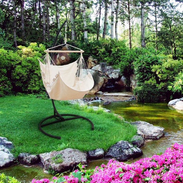 Gartenansicht mit Hängesessel auf Gestell neben einem Teich.