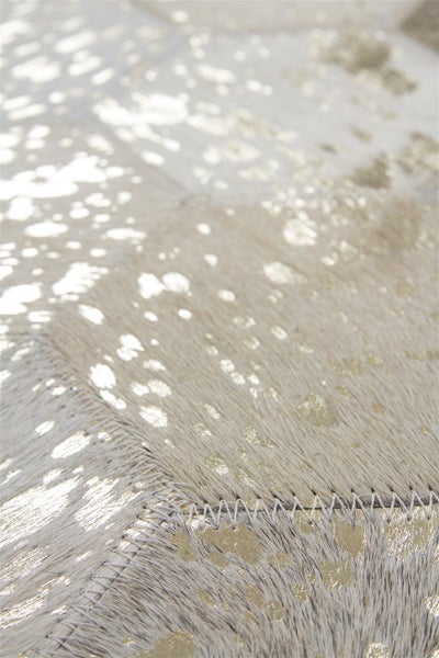 Detailansicht eines Patchwork Teppichs aus echtem Fell mit metallicfarbenem Aufdruck.