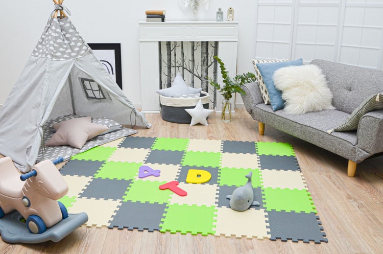 Hell eingerichtetes Kinderzimmer mit Schaumstoff-Puzzlematte, Tipi-Zelt, Schaukelpferd und grauem Sofa auf hellem Holzboden.