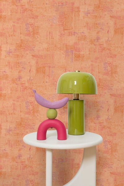 Dekorative Tischszene mit Leuchte, Ornamenten und Beistelltisch vor einer Wandtapete