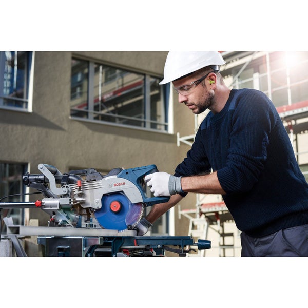 Ein Bauarbeiter bedient eine Kappsäge auf einer Baustelle und trägt dabei Sicherheitsausrüstung.