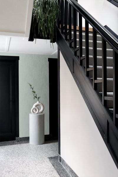 Eingangsbereich mit Treppe, dekoriert mit Vase auf Sockel und Hängepflanze