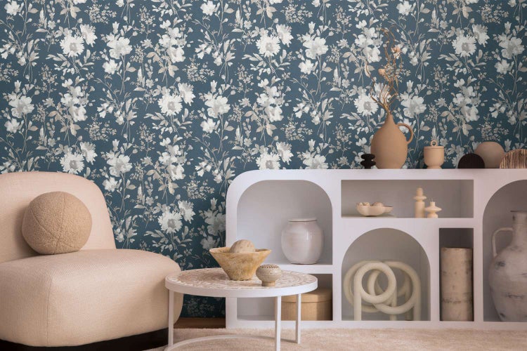 Wohnraum mit floraler Vliestapete, moderner weißer Ablage, rundem Couchtisch und Sessel in einer wohnlichen Atmosphäre.