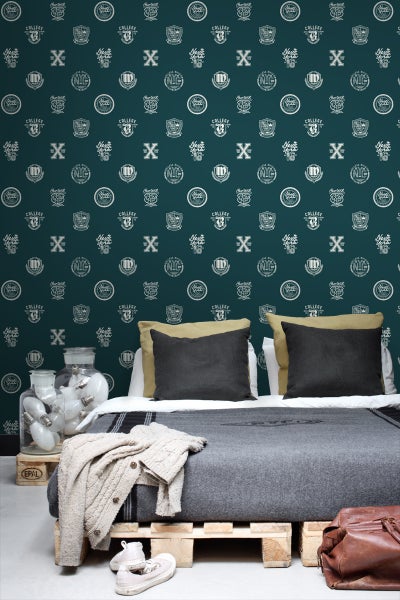 Dekoratives Schlafzimmer mit dunkel gemusterter Tapete, Palettenbett und Glühbirnen in einem Glas