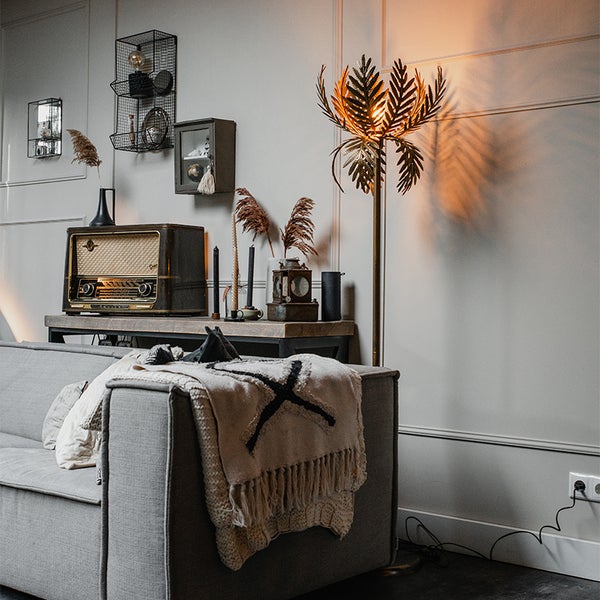 Wohnzimmer mit Sofa, Stehlampe und Dekorationen auf einem Tisch