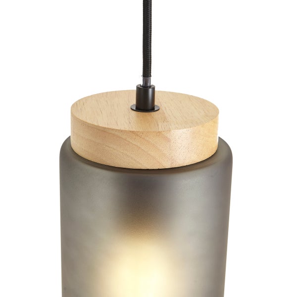 Pendelleuchte mit zylindrischem grauem Milchglasschirm, oberem Abschluss aus hellem Holz und schwarzem Textilkabel.