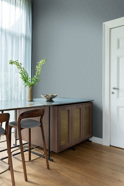 Wohnraum mit geometrischer Tapete, Sideboard, Barhockern und Tür