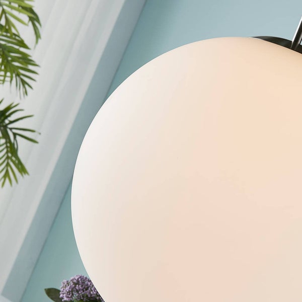 Detailaufnahme einer runden Kugelleuchte aus weißem Opalglas in einem hellen und organisierten Raum.