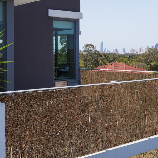 Sichtschutzzaun aus natürlichem Material vor einem modernen Haus mit Blick auf die Stadt