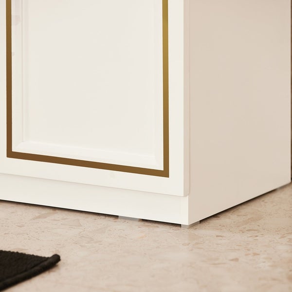 Detailansicht eines weißen Badezimmerschranks mit goldener Umrandung
