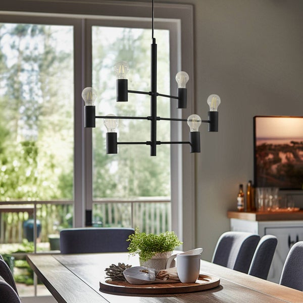 Schwarze Pendelleuchte mit sechs Glühbirnen über einem Esstisch.