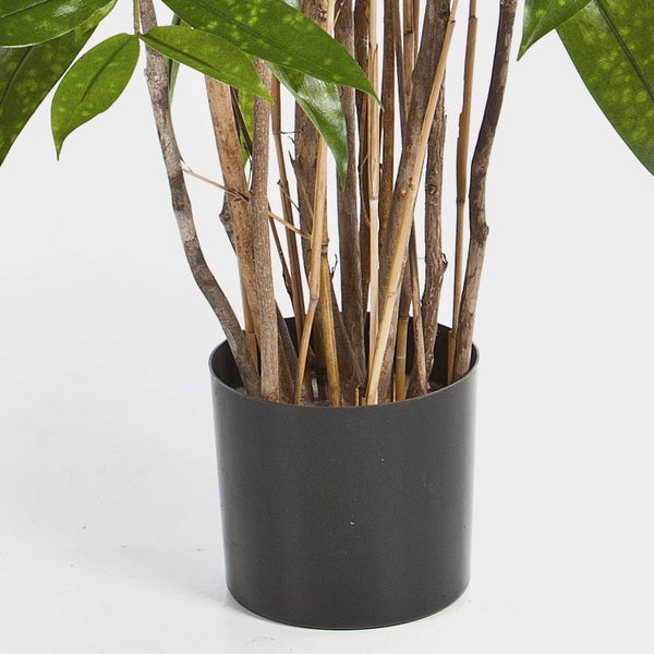 Künstliche Pflanze mit grünen Blättern und braunen Holzstämmen in einem dunklen Pflanztopf.