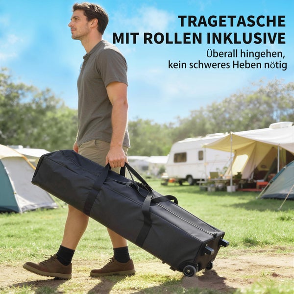 Ein Mann zieht eine schwarze Tragetasche mit integrierten Rollen auf einem Campingplatz. Inklusive Tragegriffen für einfachen Transport.
