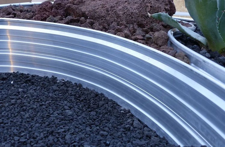 Detailansicht eines Hochbeets mit Lavasteinen und Pflanze