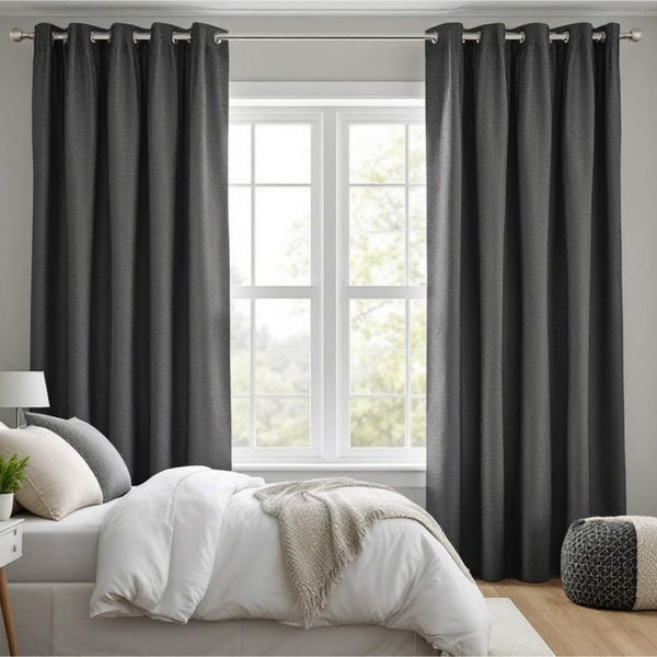 Schlafzimmer mit grauen Vorhängen und Bett vor einem Fenster.
