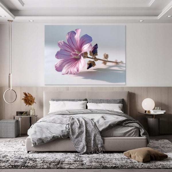 Schlafzimmer mit modernem Doppelbett, grau-weißer Bettwäsche und einem großen Wandbild einer rosa Blüte über dem Kopfteil.