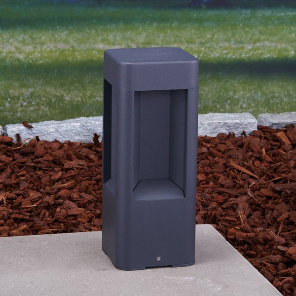 Moderne quadratische Wegeleuchte in Anthrazit aus Metall auf einem Betonsockel im Garten.