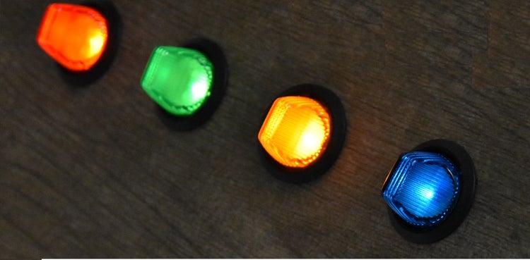 Vier beleuchtete runde Schalter oder Signalleuchten in verschiedenen Farben.