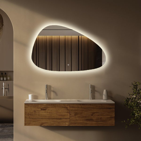 Organisch geformter Badezimmerspiegel mit indirekter LED Beleuchtung, montiert über einem Waschtischunterschrank aus Holz mit zwei Waschbecken.