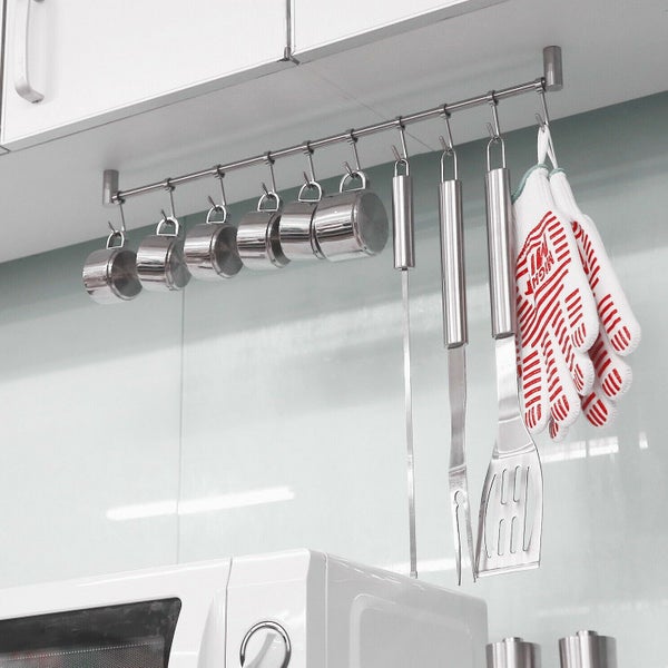 Küchenreling aus Edelstahl mit Haken unter einem Schrank, behängt mit Messbechern, Grillbesteck und einem Grillhandschuh.
