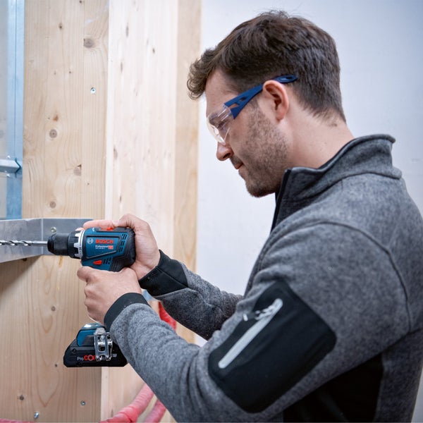 Mann bohrt mit einem Akku-Bohrschrauber in eine Holzwand