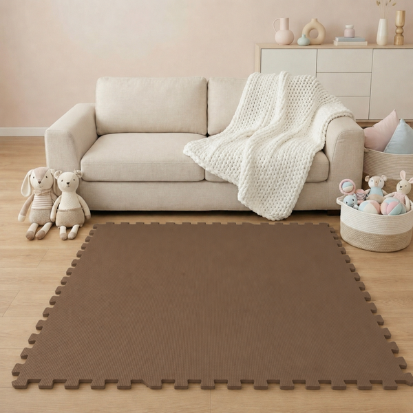 Braune Schaumstoff-Puzzlematte auf hellem Holzboden in einem gemütlichen Wohnzimmer mit beigem Sofa und Spielzeug.