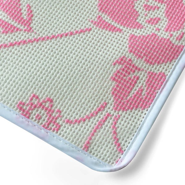 Detailansicht einer weiß strukturierten Matte mit pinkem Blumenmuster und weißem Rand.