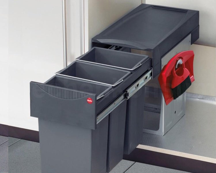Ausziehbares Mülltrennsystem mit drei Behältern und seitlicher Halterung für ein Kehrset in einem Küchenunterschrank.