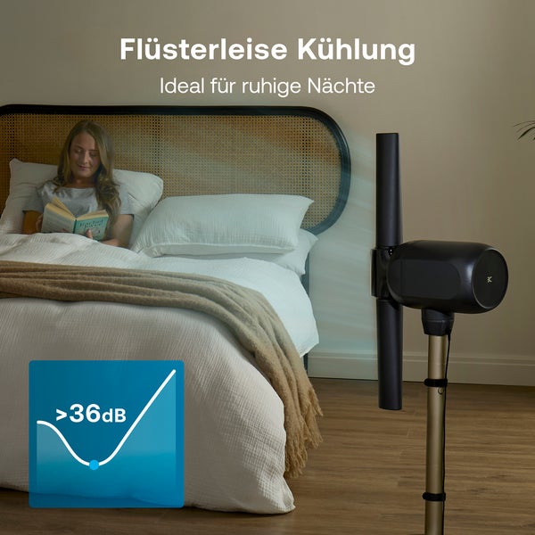 Frau liest im Bett in einem hellen Schlafzimmer, während ein leiser Ventilator kühlt. Geräuschpegel von 36 Dezibel für ruhige Nächte.