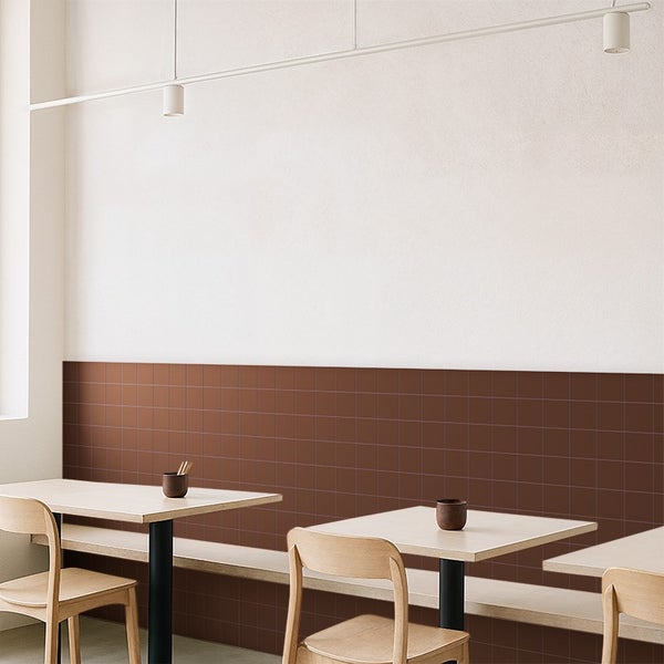 Wand mit braunen quadratischen Fliesen in einem modernen Restaurantbereich mit Holztischen und Stühlen.