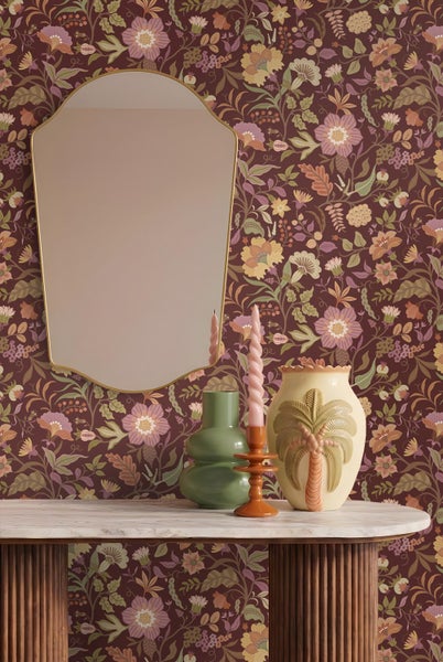 Tapete mit detailreichem Blumenmuster im Vintage-Stil auf dunklem Grund, kombiniert mit einem Spiegel mit Goldrahmen und Dekovasen.