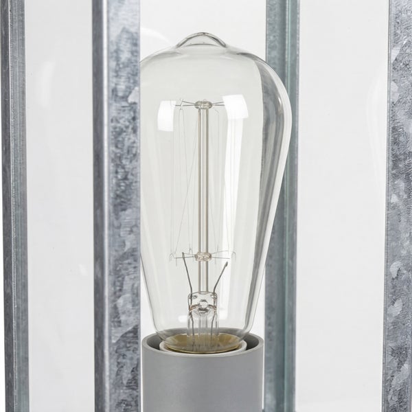 Nahaufnahme eines Leuchtmittels in Edisonform aus Glas in einer Fassung mit einem Rahmen aus verzinktem Metall.