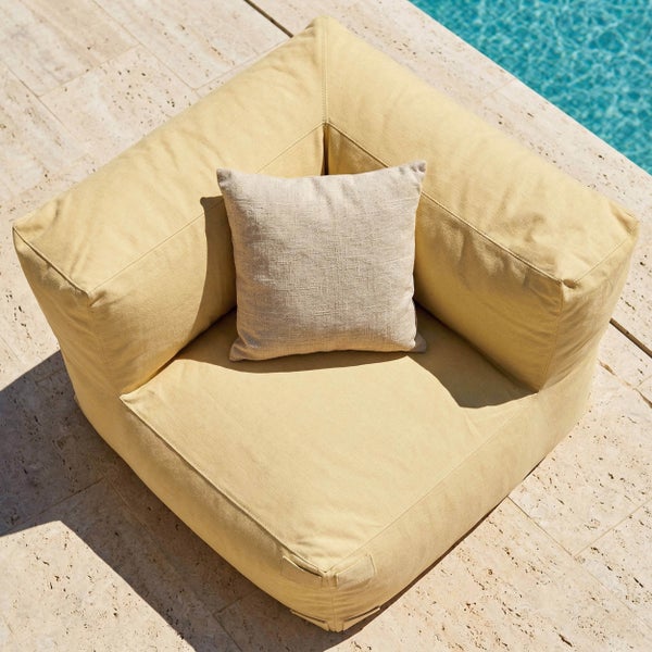 Outdoor-Lounge-Ecksessel mit Zierkissen auf einer Terrasse am Pool.