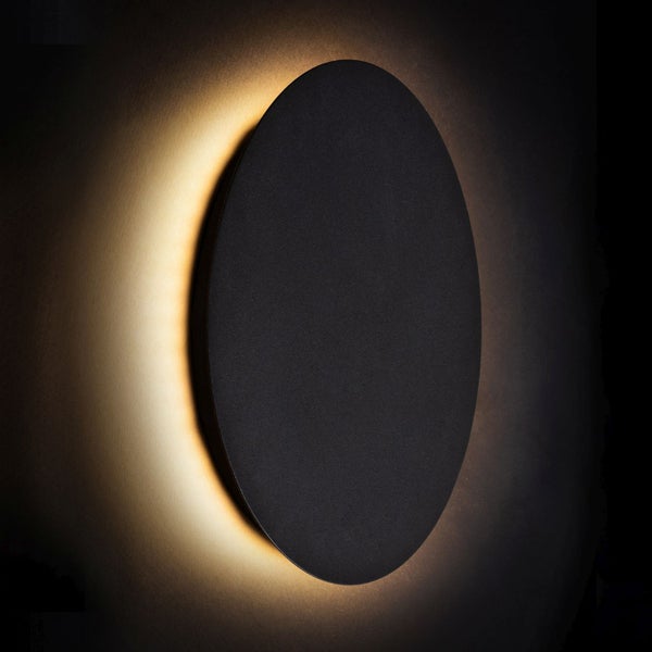 Schwarze runde Wandleuchte gibt ein warmes Licht ab.