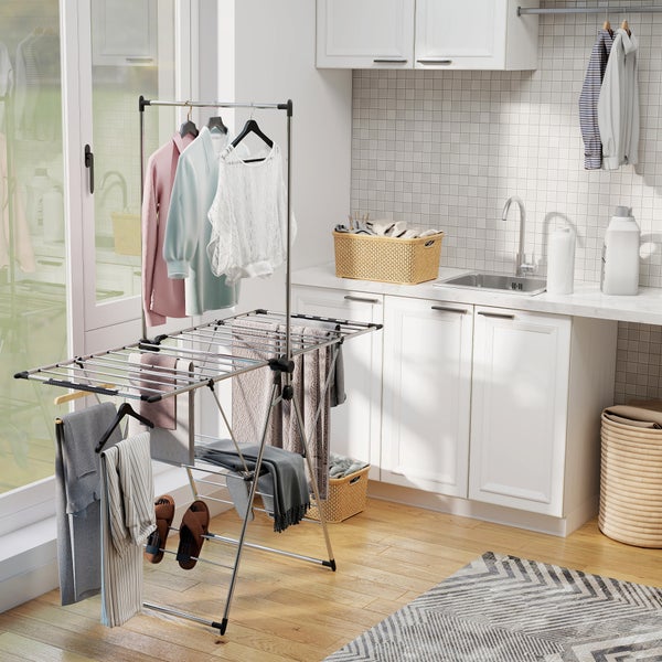 Heller Hauswirtschaftsraum mit stehendem Wäscheständer aus Metall, weißen Schränken, einem Spülbecken und geflochtenen Wäschekörben.