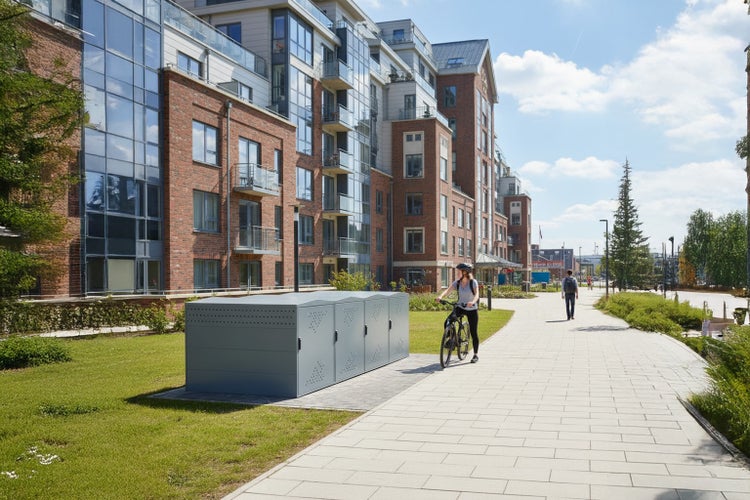 Fahrradgarage vor einem Wohnhaus mit Fußweg und Grünfläche