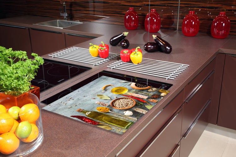 Küchenrückwand aus Glas mit Gewürz-Motiv hinter einem Induktionskochfeld in einer modernen Küche mit Dunstabzugshaube.