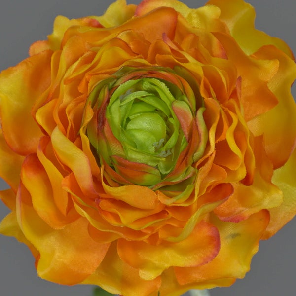 Künstliche Ranunkelblüte aus Textilmaterial mit orangefarbenen Blütenblättern und grünem Zentrum.