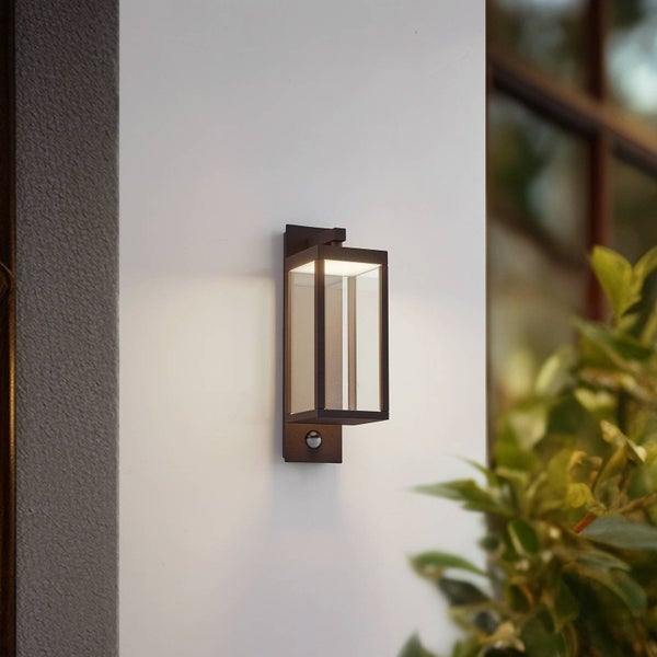 Moderne Außenwandleuchte mit Bewegungsmelder, rechteckiges Design aus Metall und Glas, montiert an einer Hauswand.
