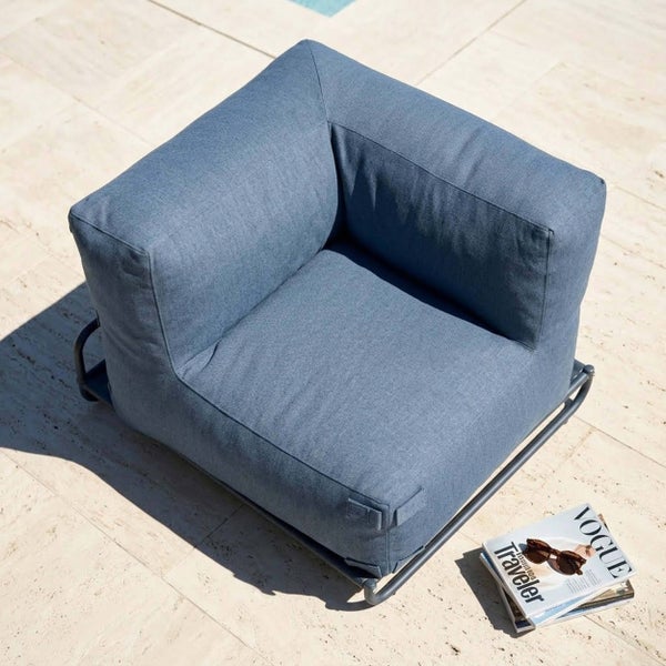 Eckmodul eines Garten-Lounge-Sessels mit blauem Stoffbezug und dunklem Metallgestell auf einer Terrasse.