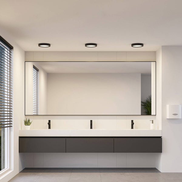 Modernes Badezimmer mit großem Spiegel, weißem Waschtisch mit drei schwarzen Armaturen, dunklem Unterschrank und drei schwarzen Deckenleuchten.