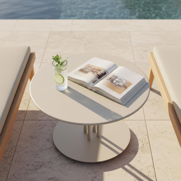 Runder Beistelltisch aus Metall in Beige auf einer Terrasse am Pool zwischen zwei Sonnenliegen.