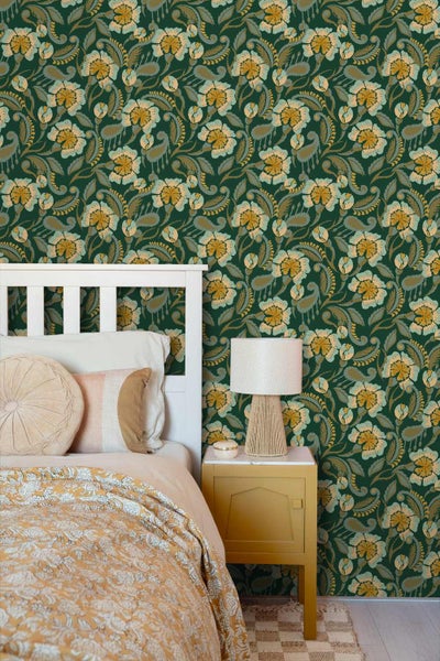 Florale Tapete in einem Schlafzimmer mit weißem Bett, gemusterter Bettwäsche und gelbem Nachttisch mit Lampe.